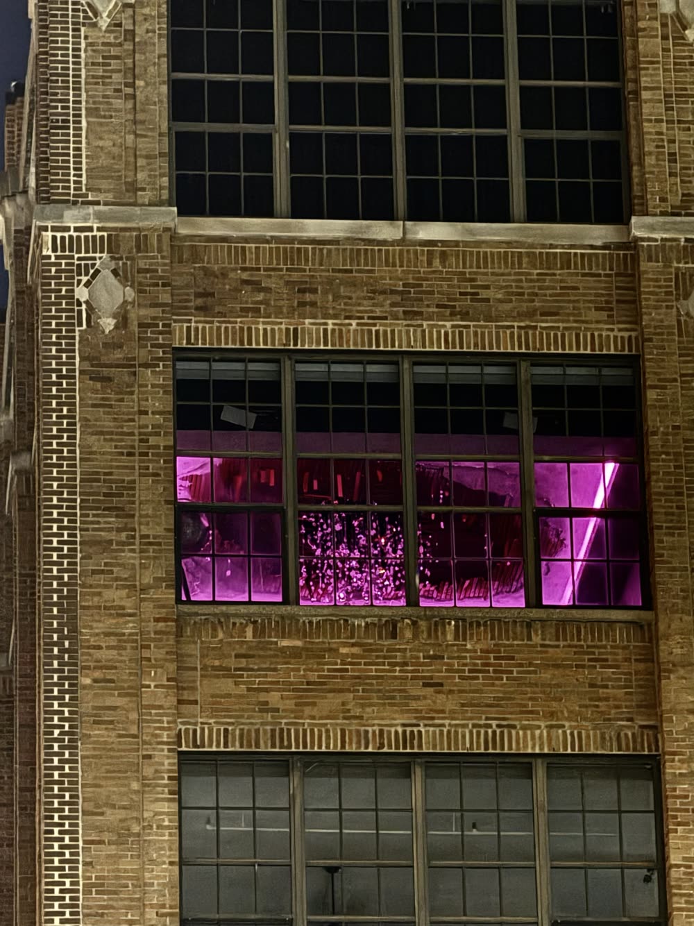 The brick building at night from street level, showcasing the torn ceiling and crystal cascade.